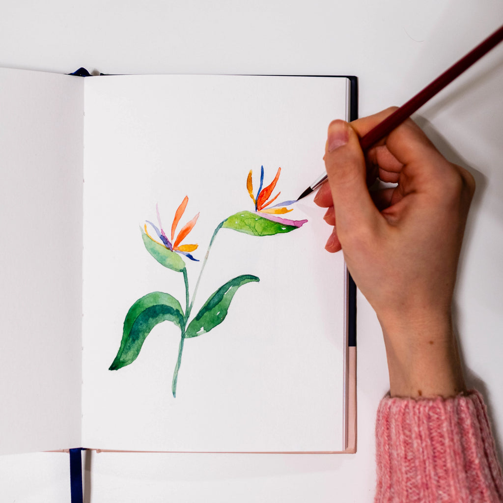 Künstlerin malt mit Aquarellfarben im Lavianne Sunrise Marine Sketchbook, Fokus auf die Papierstruktur.